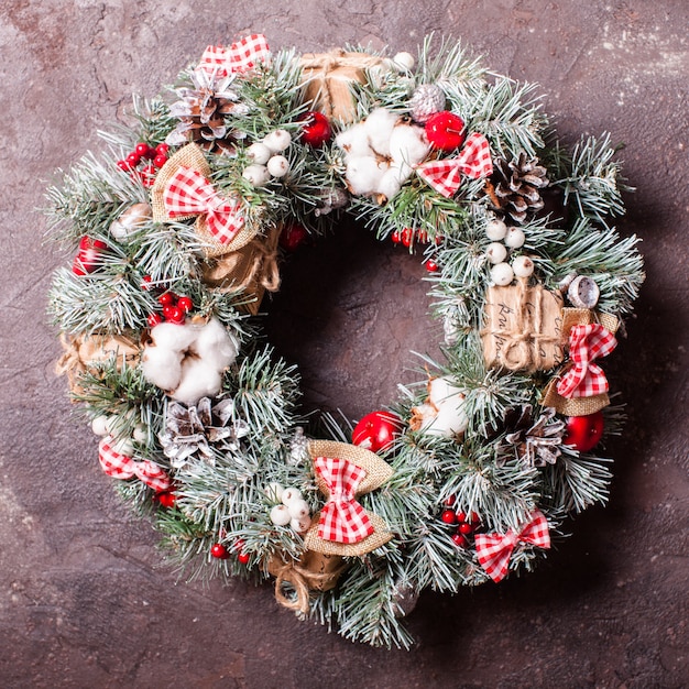 Rode en witte kerstkrans met strikken en katoenen bloemen