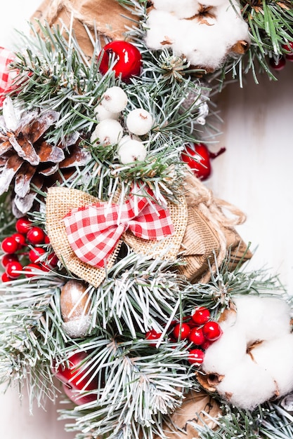 Rode en witte kerstkrans met strikken en katoenen bloemen