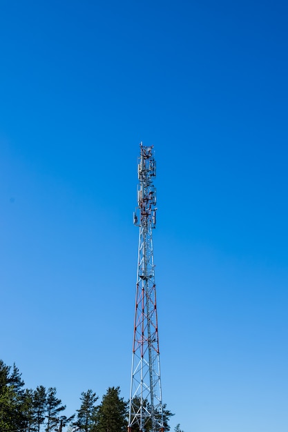 Rode en witte kleurenantenne repeater toren op blauwe hemel zonder wolk.