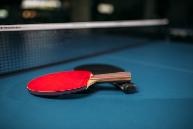 Rode en zwarte tennisrackets op tafel tegen netto