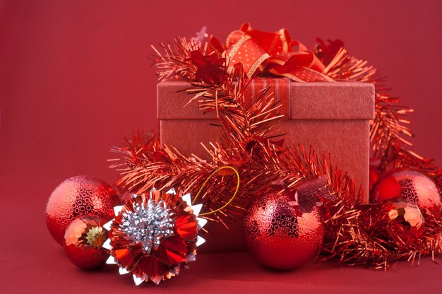 Rode geschenkdoos met decoraties op rode achtergrond. Kerst vakantie concept