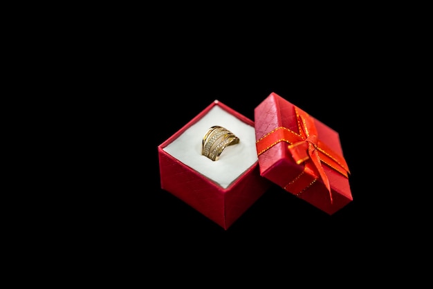 Rode geschenkdoos met gouden ring op zwarte achtergrond