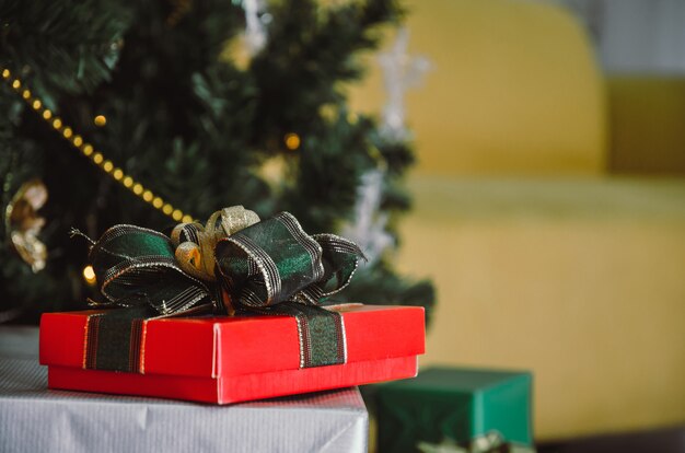 Rode geschenkdoos met groen lint op bureau met kerstboom