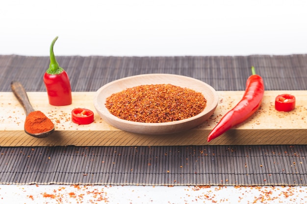 Rode gesneden Spaanse peperpeper en Spaanse peperpoeder dat op houten basis wordt verspreid. Gastronomie en specerijen.