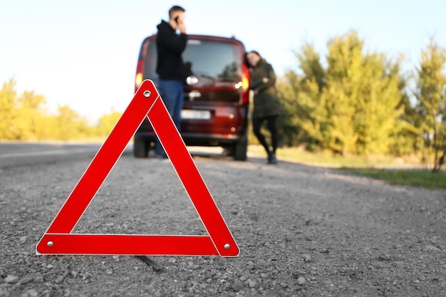 Rode gevarendriehoek op asfaltweg Paar in de buurt van kapotte auto