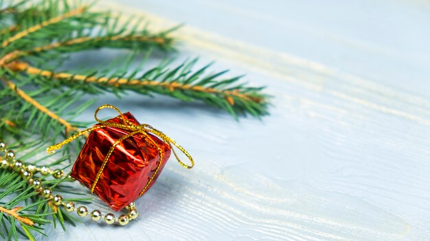 Rode gift met kerstboomspeelgoed en takje sparren. Kopieer ruimte