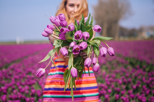 Foto rode haarvrouw die een kleding draagt die een mand met boeket van tulpenbloemen houdt