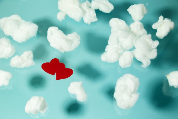 Rode harten vliegen tussen witte katoenen wolken op een pastelblauwe achtergrond