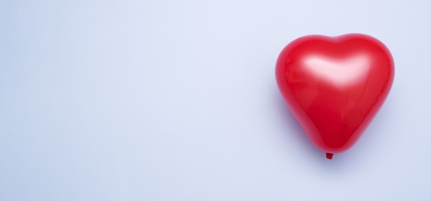 Rode hartvormige ballon op blauwe achtergrond - valentijnsdag concept minimalisme