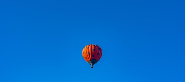 Rode hete luchtballon versierd als lieveheersbeestje vliegen in heldere blauwe lucht kopie ruimte