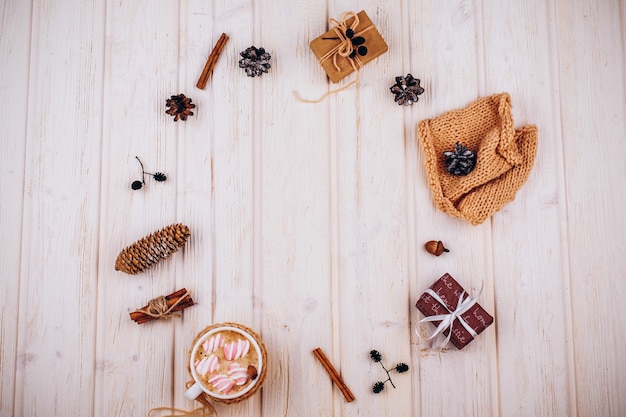 Rode huidige doos, kegels, kaneel en andere rustieke kerst decor op houten tafel met een kop warme chocolademelk