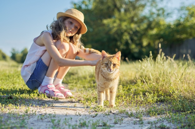 Rode kat camera kijken, meisje kind kat aan te raken op zonnige zomerdag op landweg in de natuur