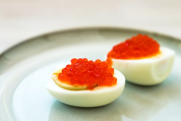 Rode kaviaar gevuld gehalveerde eieren traditionele Russische snack geserveerd op blauw grijze plaat. Detailopname. Selectieve aandacht. Kopieer ruimte