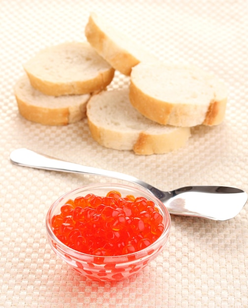 Rode kaviaar in een glazen schaal met brood en lepel op doek
