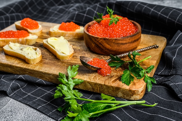 Rode kaviaar in houten kom en broodjes op snijplank. Bovenaanzicht
