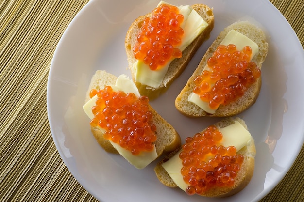 Rode kaviaar op brood en boter close-up vier sandwiches op witte plaat Uitzicht van bovenaf