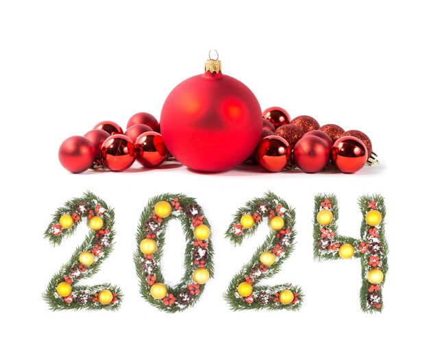 Foto rode kerstbal en 2024 nummer gemaakt door kerstboom takken geïsoleerd op witte achtergrond