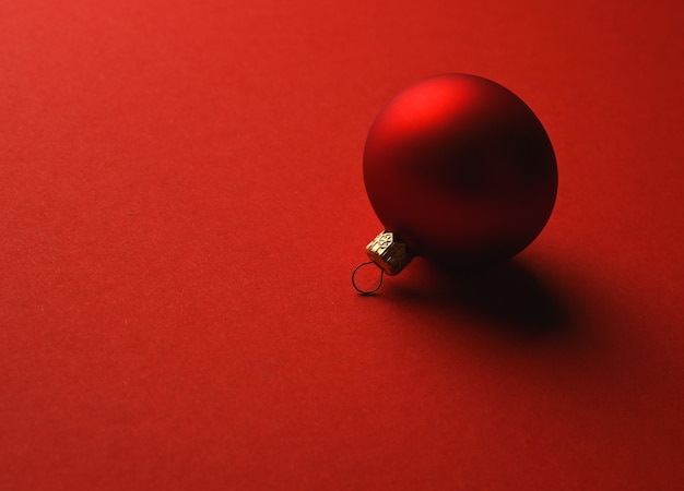 Rode kerstbal ligt op een rood oppervlak met schaduwen. Hoge kwaliteit foto