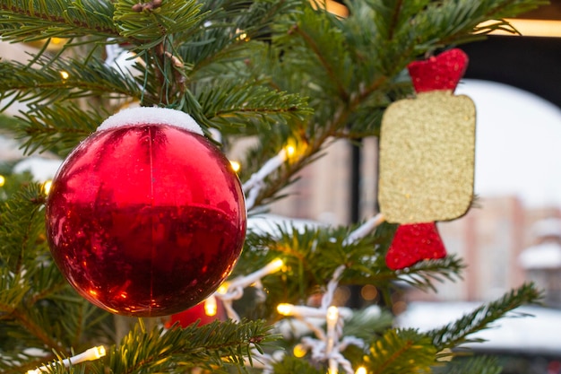 Rode kerstbal op een groene besneeuwde tak van een kerstboom op kerstavond