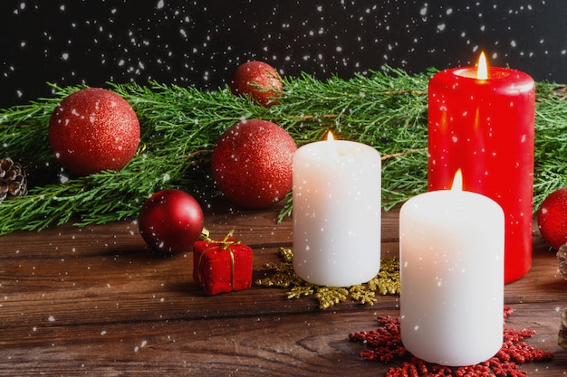 Rode kerstballen, kaarsen, vuren takken, krans en sneeuwvlokken op een donkere achtergrond