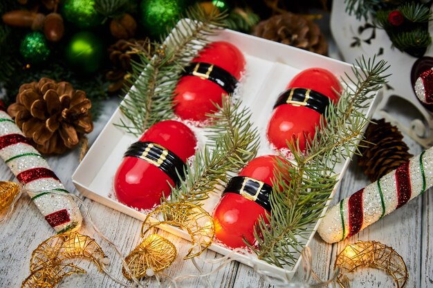 Rode kerstdessert in de vorm van mousse op de achtergrond van kaarsenslingers dennentakken