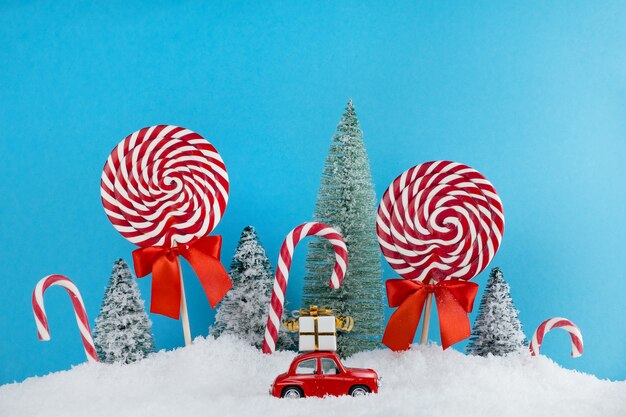 Rode kerstman auto met cadeau op dak in kerstboom bos met snoep en lollies snoep