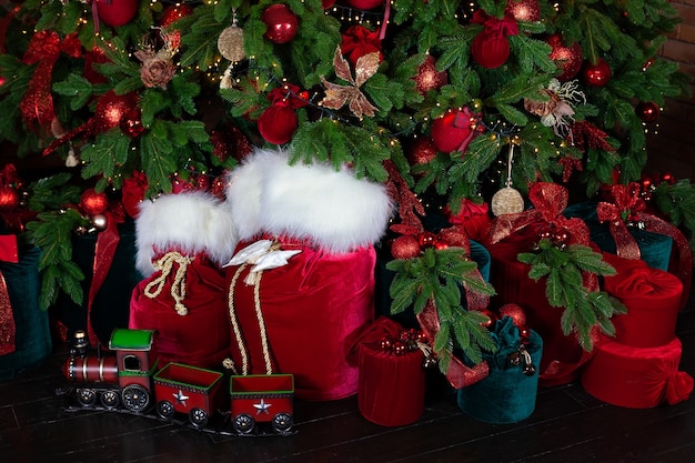 Rode kerstman tas en speelgoed trein in de buurt van kerstboom