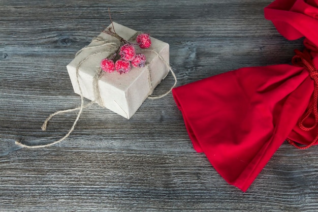 Rode kerstmantas en cadeau verpakt in ambachtelijke verpakkingen op een houten ondergrond