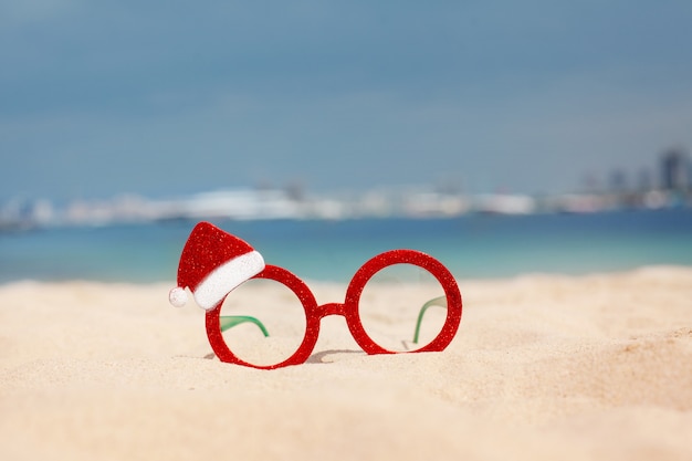 Foto rode kerstmisglazen en santahoed op het strand