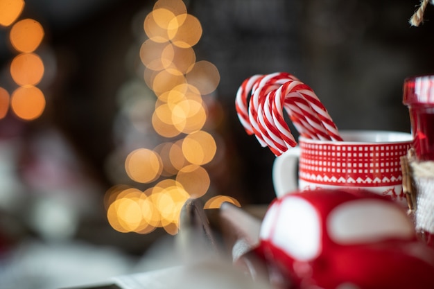 Foto rode kerstmokken met snoep liggen op de tafel op de achtergrond van de kerstboom