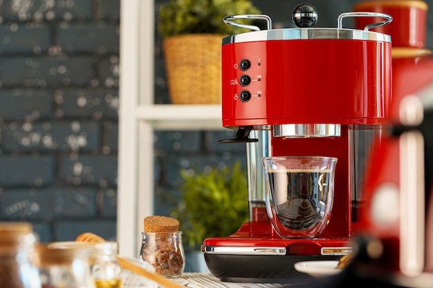 Rode koffiemachine met een glas op aanrecht