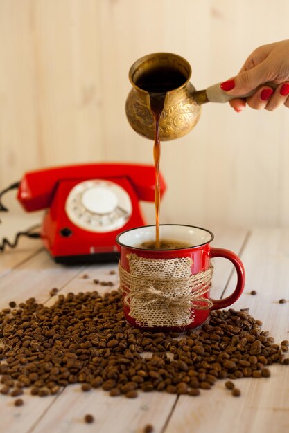 Rode kop en Cezve koffie met retro telefoon op houten achtergrond Turkse koffie gieten