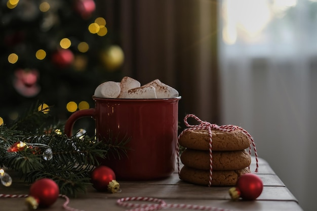 Rode kop warme winterdrank met marshmallows en koekjes op de achtergrond van de kerstboom