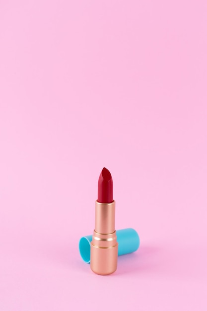 Rode lippenstift in een gouden buis geïsoleerd op een roze achtergrond Cosmetisch product voor heldere schoonheid