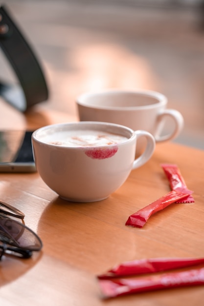 Rode lippenstiftmarkering op een koffiekopje op tafel in café