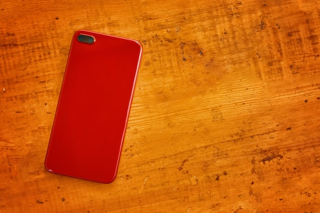 Rode mobiele telefoon op houten tafel moderne gadget voor leven en zakelijk bovenaanzicht op persoonlijke accessoire...