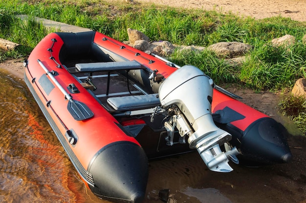Rode opblaasbare rubberen boot met een motor in de buurt van de oever van het meer visserij toerisme actieve recreatie