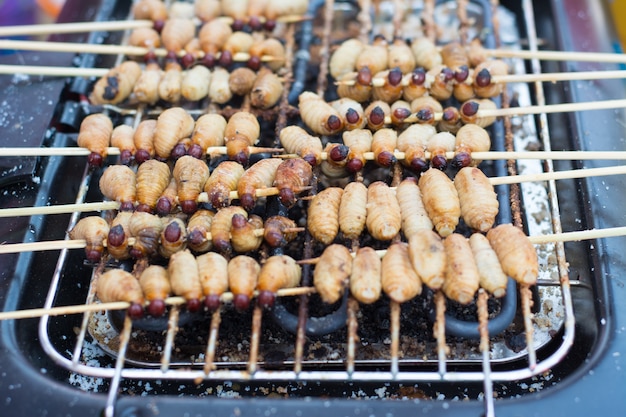 Rode palmgraanklander, de grill van de sagoworm op vleeskuiken bij straatvoedsel