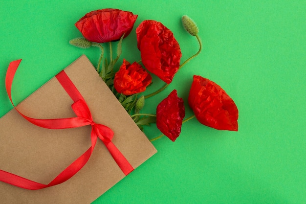 Rode papavers in een envelop die met een rood lint op green wordt gebonden