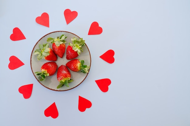 Rode papieren harten en verse aardbeien op een bord. Liefde. Valentijnsdag. Voedsel achtergronden. Kaart