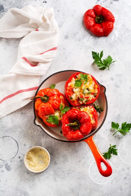 Rode paprika gevuld met rijst en groenten op gietijzeren pan op grijze betonnen ondergrond