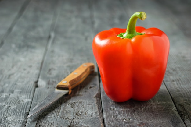 Rode paprika met een mes op een houten tafel. Vegetarisch eten. Het concept van gezond eten.