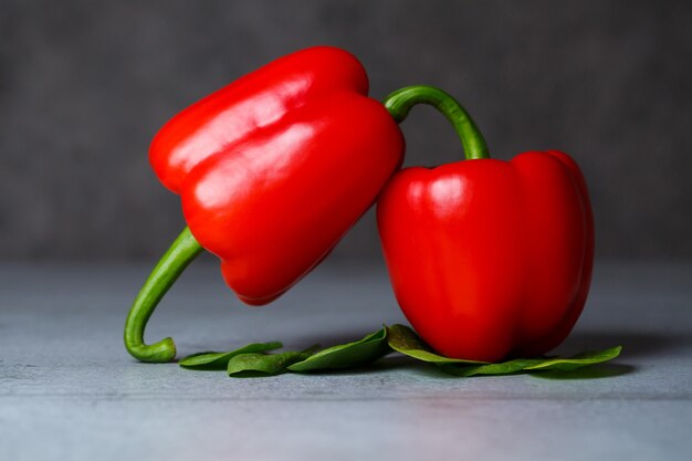 Foto rode paprika met spinazie op een grijze tafel