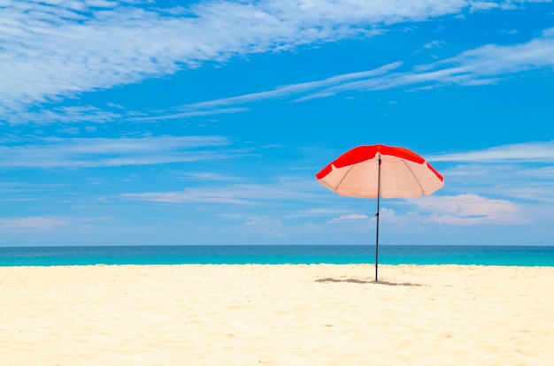 Rode paraplu strand wit zand en blauwe lucht