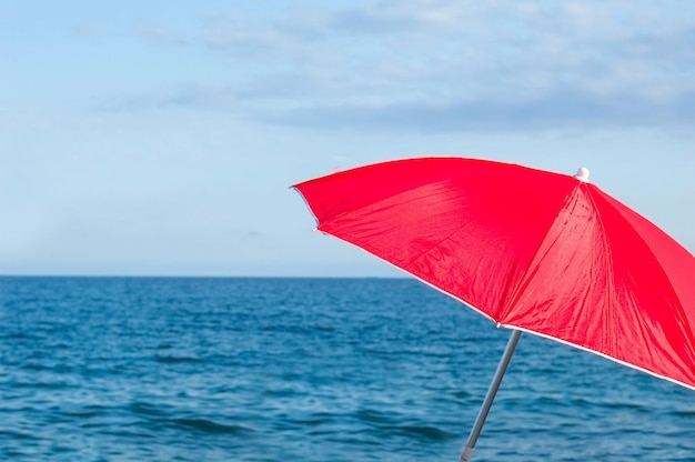 Rode parasol paraplu op tropisch eiland strand Kleurrijke parasol op het strand op zonnige zomerdag Vakantie ontspanning met turquoise zee en blauwe lucht landschap Zomer vakantie concept