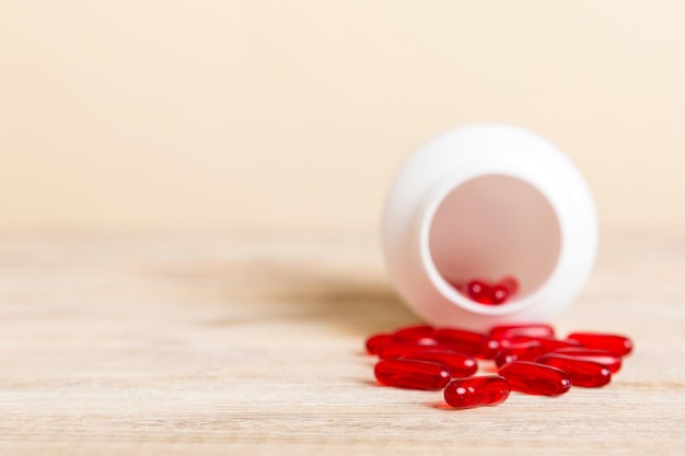 Rode pillen gemorst rond een pillenfles Medicijnen en voorgeschreven pillen plat op de achtergrond Rode medische capsules