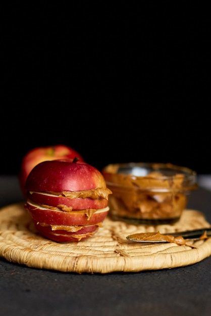 Rode plakjes sandwich of hamburger van appel met pindakaas op donkere achtergrond