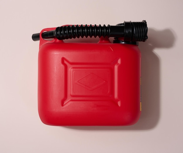 Foto rode plastic jerrycan voor vloeibare brandstoffen en smeermiddelen op een beige achtergrond