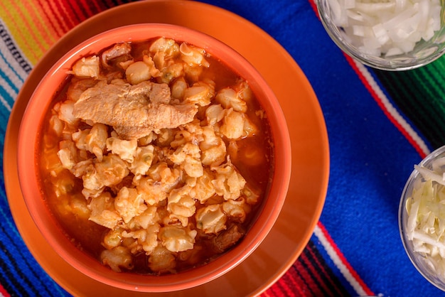 Rode pozole geserveerd in een diep gerecht op kleurrijke serape Typisch Mexicaans eten gemaakt van maïs