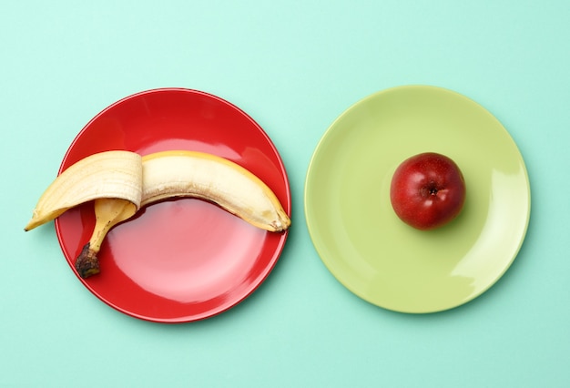 Rode rijpe appel en banaan liggen in een ronde keramische plaat